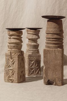 three stone vases sitting next to each other on a white surface with a cloth behind them