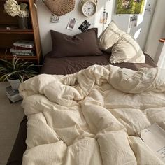 an unmade bed with many pillows and pictures on the wall