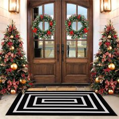 two christmas trees with wreaths on them are in front of a double door decorated for the holidays