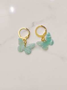 two gold hoop earrings with green glass butterflies on the front and back of each ear