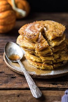 a stack of pancakes sitting on top of a white plate next to a silver spoon