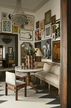 a living room with pictures on the wall and a table in front of some chairs