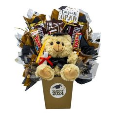 a teddy bear sitting in a box filled with chocolates and candy bar wrappers