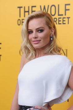 a woman with blonde hair wearing a white top and black skirt at the wolf of wall street