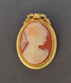 "The women in Lisner Cameos tend to be quite attractive and with great attention to detail in their rendering. This one is exceptionally beautiful. Measuring 2\" by 1 1/2\" the face is ivory colored with coral highlights set on a coral pedestal and trimmed in a beautifully detailed golden frame. The brooch is signed \"LISNER\" on the back bottom of the frame. It is in excellent vintage condition showing little or no wear. A brooch converter kit will be provided FREE when you purchase this item e Oval Brooches For Formal Occasions, Collectible Cabochon Brooches, Coral Highlights, Wear A Brooch, Golden Frame, Cameo Brooch, Ivory Color, Brooches, The Face