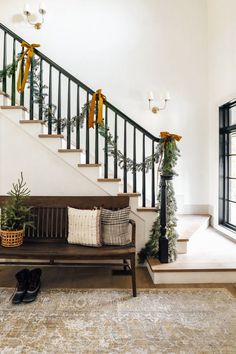 a wooden bench sitting under a stair case next to a bannister filled with greenery