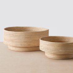 two large woven baskets sitting on top of a wooden table next to eachother