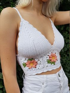 a woman wearing a white crochet top with flowers on it