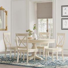 a dining room table with four chairs and a mirror on the wall in front of it