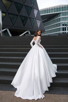 a woman in a white wedding dress standing on some steps with her hands on her hips