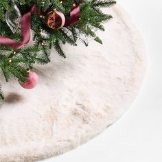 a christmas tree with ornaments hanging from it's branches on a white tablecloth