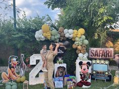 a woman standing in front of a display of balloons and mickey mouses on the lawn