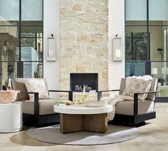 a living room with two chairs and a coffee table in front of a stone fireplace