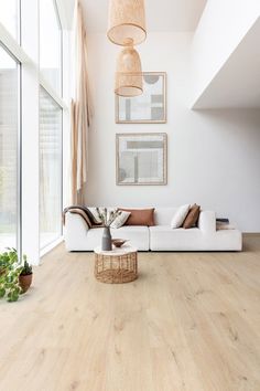 a living room with white furniture and wood floors