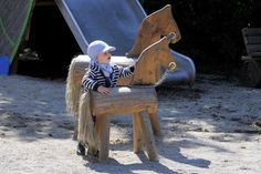 a small child sitting on top of a wooden bench next to a playground equipment slide