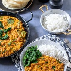 two plates with rice, spinach and curry next to some pita bread on a table