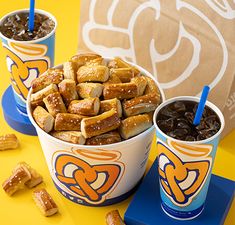 two cups filled with food next to each other on a yellow tablecloth and blue napkins