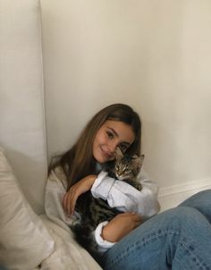 a woman sitting on a couch holding a cat