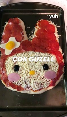 a pizza with meat and cheese in the shape of a chicken head on top of it