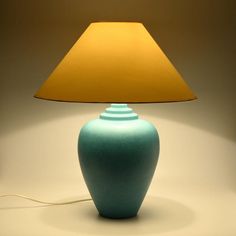 a blue lamp with a yellow shade on it and a white wall in the background