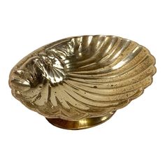 a metal bowl that is sitting on a white surface with gold leaf decoration around it