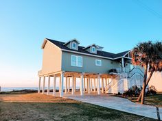 the house is next to the beach and has white pillars on each side that lead up to the second story