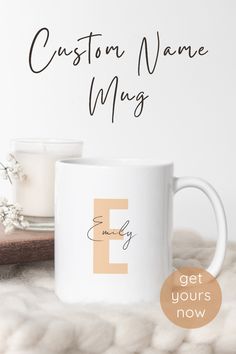 a coffee mug sitting on top of a white blanket next to a cup with the letter e