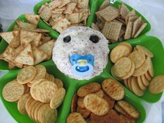 a green plate topped with lots of crackers and cheese covered in a bear face