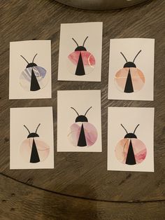 four cards with different designs on them sitting on a wooden table next to a bowl