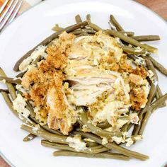 a white plate topped with green beans and chicken covered in gravy on top of mashed potatoes