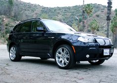 a black bmw suv parked in front of some palm trees