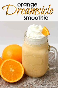 an orange smoothie in a mason jar with whipped cream and fresh oranges around it