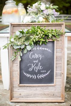 a chalkboard sign with greenery on it