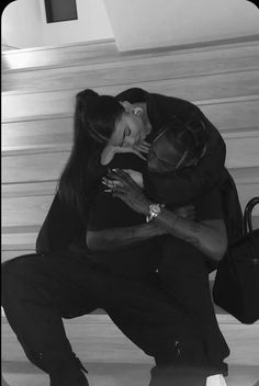 a man kneeling down next to a woman on top of a wooden floor in front of stairs