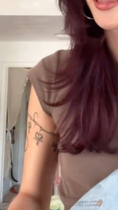 a woman with purple hair and tattoos on her arm