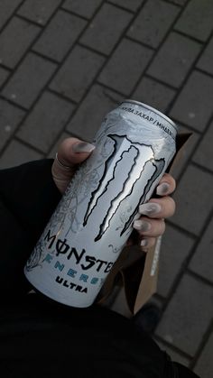 a woman holding up a can of monster energy