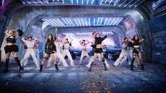 a group of women dancing on stage in front of a tunnel with lights behind them