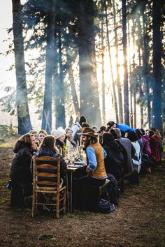 a group of people sitting around a table in the woods