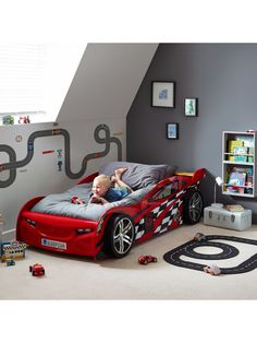 a child's bedroom with a race car bed and toy cars on the floor