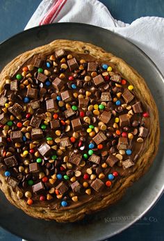 a cake covered in chocolate and candy on top of a pan with a napkin next to it