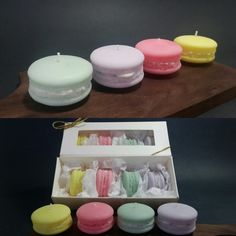 there are many different colored candles in the box and on the table next to each other