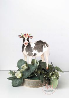 a cow figurine sitting on top of a potted plant with flowers in it