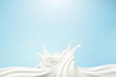 milk splashing into the air on a blue sky background with white bubbles and water droplets