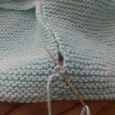 a close up of a knitted sweater being sewn with needles and yarns