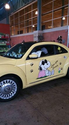 a yellow car with a cartoon dog on it's side in a parking lot