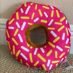 a pink donut pillow with yellow and white sprinkles