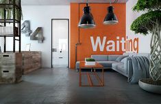 a living room with an orange wall and two lamps hanging from it's ceiling