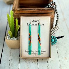 a pair of turquoise and red beaded earrings sitting on top of a wooden box