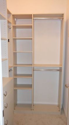 an empty walk in closet with white shelves and drawers on either side of the door