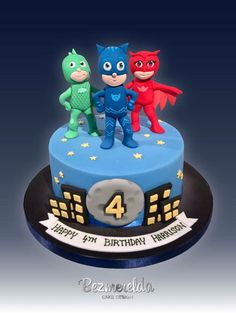 a birthday cake with three little superheros on top and the number four in the middle